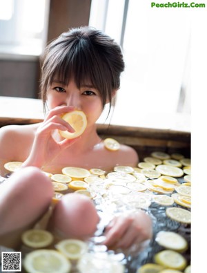 A woman holding a bunch of lemons in her hands.