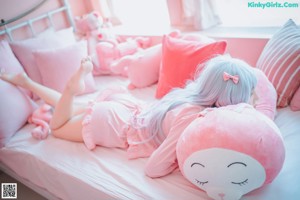 A woman sitting on a bed with a pink stuffed animal.