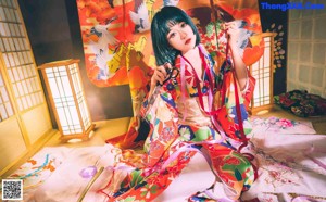 A woman in a colorful kimono laying on a bed.