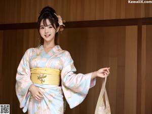 A woman in a blue kimono sitting on a chair.