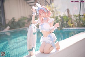 A woman in a bunny costume sitting on the edge of a pool.