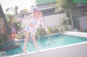 A woman in a bunny costume sitting by a pool.