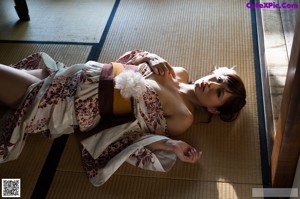 A woman in a kimono sitting on a pillow in a room.