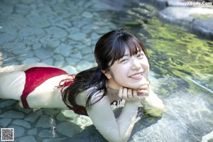 A woman in a pink bikini sitting on the ground.