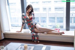 A woman sitting on a window sill wearing red high heels.