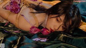 A woman in lingerie sitting on a bed with flowers.