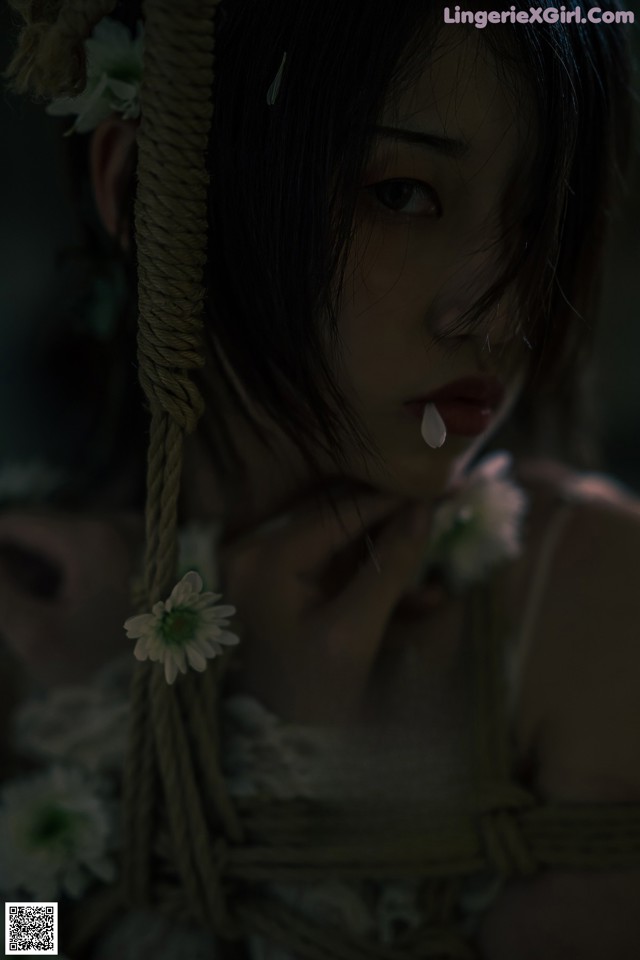 A woman tied up with a rope and flowers.