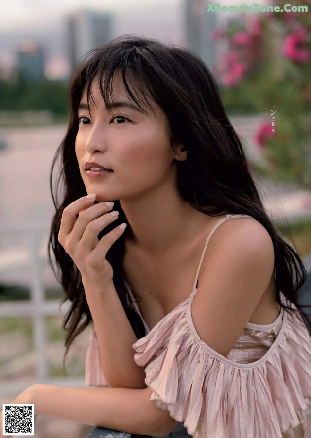 A woman in a pink dress sitting on a bench.