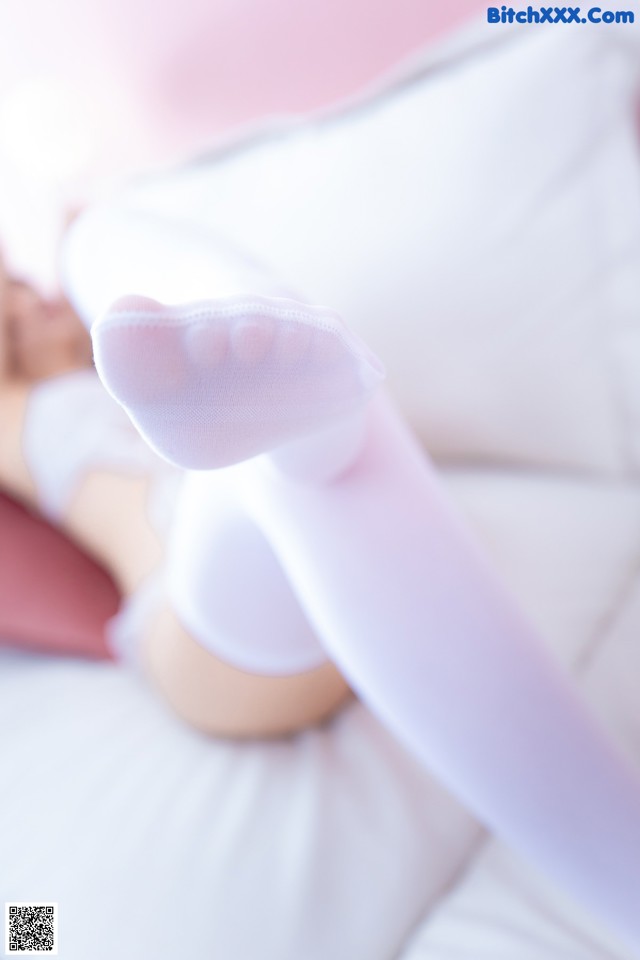 A woman in white stockings is laying on a bed.