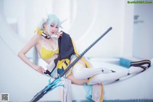 A woman in a yellow and white outfit sitting on the ground.