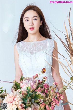 A woman in a white dress sitting on a wooden bench.