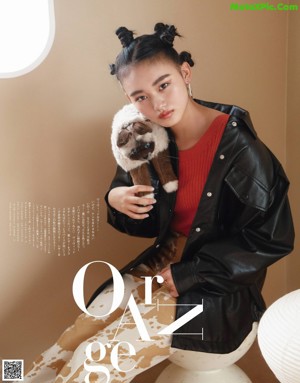 A woman in a red sweater and a black cat in a bathroom.