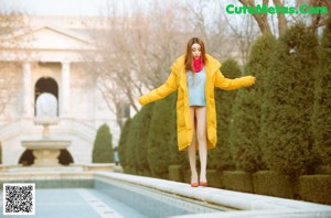 A woman in a blue sweater and red high heels leaning against a wall.