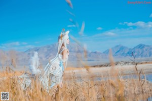 A woman in a white dress is standing in a field.