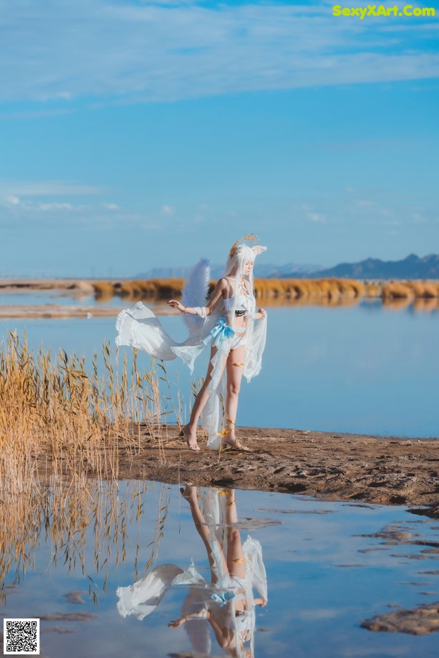 A woman in a white dress is standing in the water.