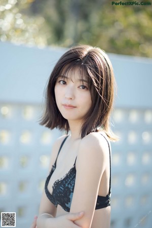 A woman in a black bra and panties sitting on a rock.