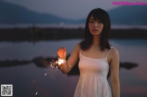 A naked woman standing on a wooden platform holding a white sheet.