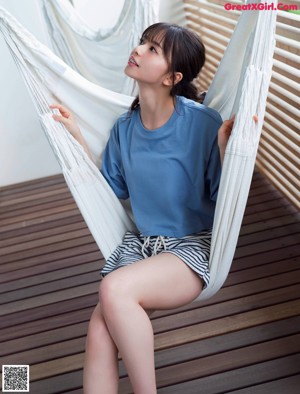 A woman sitting on a yellow chair in front of a book shelf.