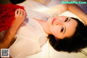 A woman in a black lingerie sitting on a bed.