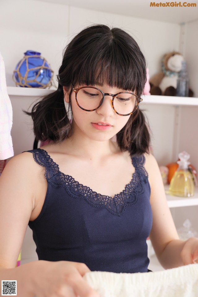 A woman wearing glasses is holding a white towel.