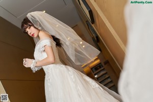 A woman in a wedding dress is posing for the camera.