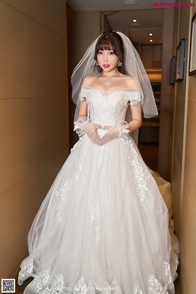 A woman in a wedding dress standing in a hallway.