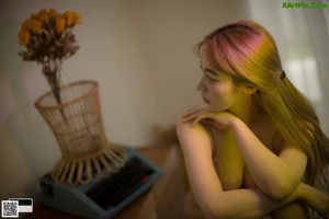 A woman in a pink bra sitting on a chair.