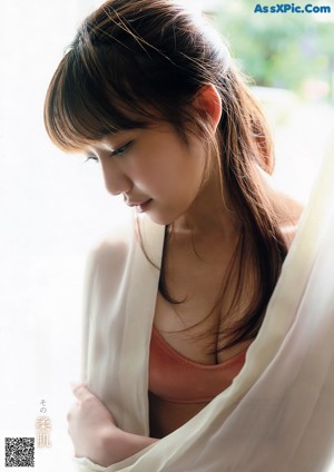 A woman in a white tank top and floral shorts posing for a picture.