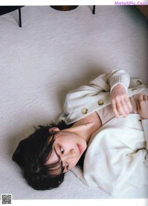 A woman in a red sweater sitting on the floor.