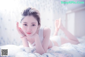 A woman laying on top of a bed in a white underwear.