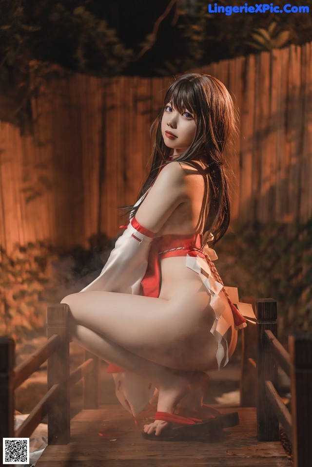 A woman in a red and white outfit sitting on a wooden bridge.