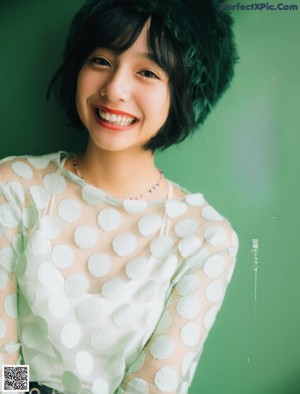 A woman in a white polka dot shirt smiles at the camera.