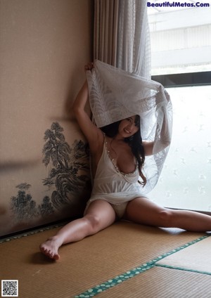 A woman in a red lingerie sitting on the floor.