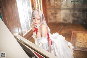 A woman in a white dress playing a white piano.