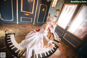 A woman in a white dress sitting at a piano.