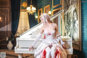 A woman in a white dress sitting on a white piano.